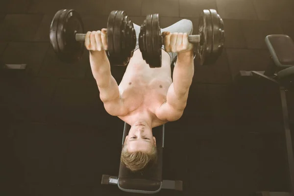 De man met dumbbells in de Sport Club. Gelukkig bodybuilder tillen dumbbells in de sportschool. Fitness, sport, oefening en gezond lifestyle concept — Stockfoto