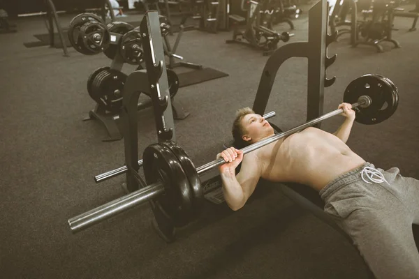 Sportieve sterke kerel doet oefeningen met een barbell in de sportschool. sport man. Bodybuilder in opleiding in de sportschool. Gezondheid en fitness. — Stockfoto