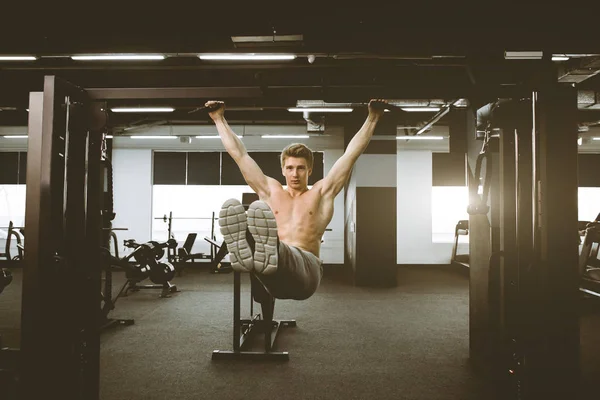 Shirtless gespierde knappe jonge man doet oefeningen op rekstok in een Gym Club. — Stockfoto