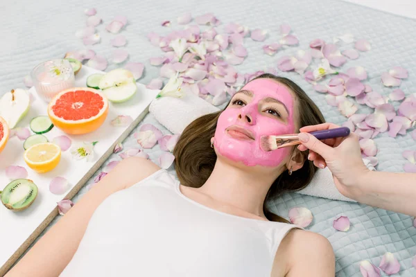 Ritratto ravvicinato di bella ragazza che applica una maschera facciale di fango rosa. Spa Donna applicazione di argilla facciale Maschera. Trattamenti di bellezza . — Foto Stock