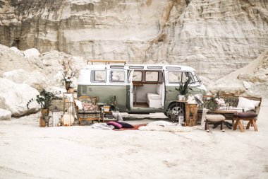 Boho rustik tarzında düğün dekor. Yeşil hippi otobüs, dekore kanepe, koltuk, halı, yastık, mumlar, sulu, kanyon manzara arka plan üzerinde bitki dekorasyon ile masa