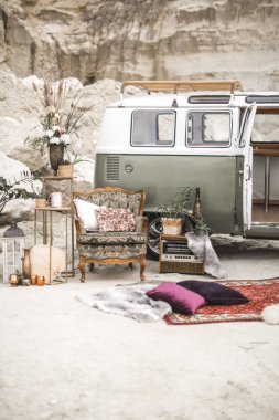 Yeşil hippi otobüs, yastık, retro radyo, bitkiler, sulu, çiçek ve mumlar, çöl manzara arka planda kürk halı ile altın metal süslemeleri ile vintage koltuk. Boho dekoru