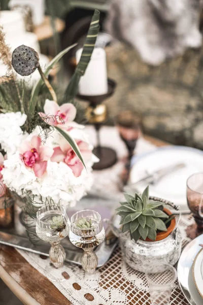 Beautiful glasses, candles, flowers stand on a fruitful decorated table in rustic boho style. Bright composition of flowers with a decor in the style of the rustic — Stock Photo, Image