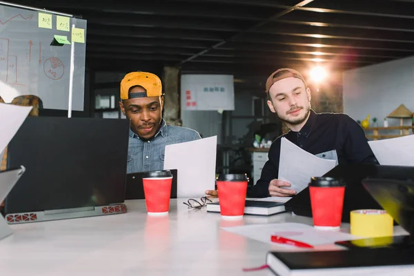 Multirasistiska manliga kollegor sitter vid bordet i kontoret koncentrerade på diskussion, skickliga professionella män partner som planerar för företagsstart på mötet — Stockfoto