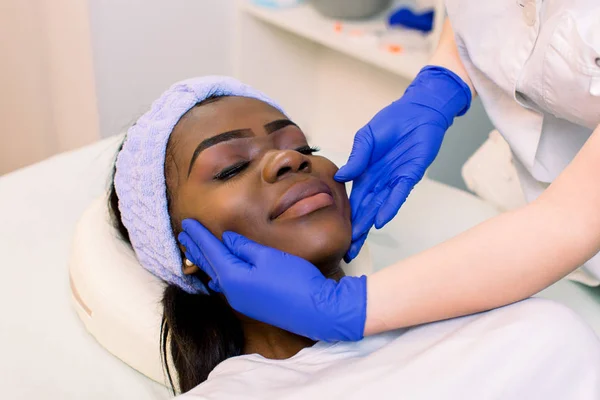 insanlar, güzellik, yaşam tarzı, kozmetoloji ve gevşeme kavramı - güzel genç Afrikalı kadın kapalı gözleri ile yalan ve spa yüz ve baş masajı olan