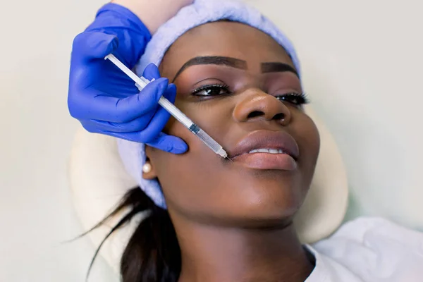 Young African woman getting lip injection in beautician salon, closeup — Stock Photo, Image