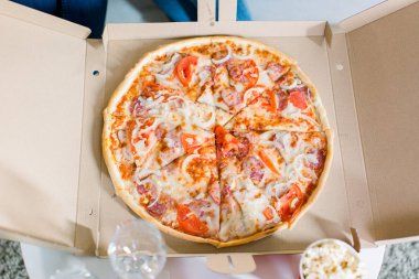 Masanın üstünde karton kutuda İtalyan pizzası. Üstte görüntü