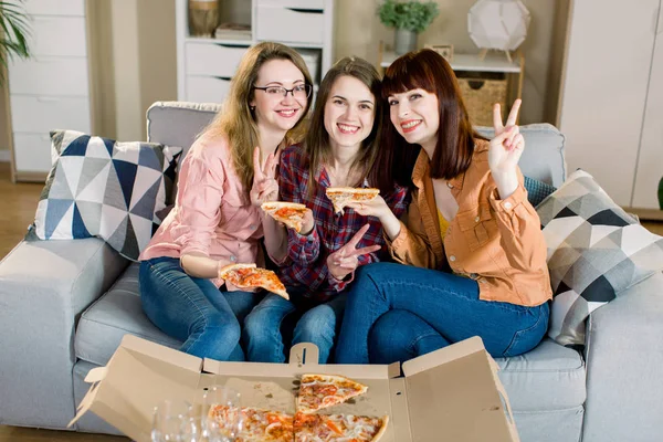 집에서 소파에 피자를 먹고 캐주얼 옷을 입고 세 행복한 젊은 여성 친구의 초상화. 여자 우정, 함께 먹는 — 스톡 사진