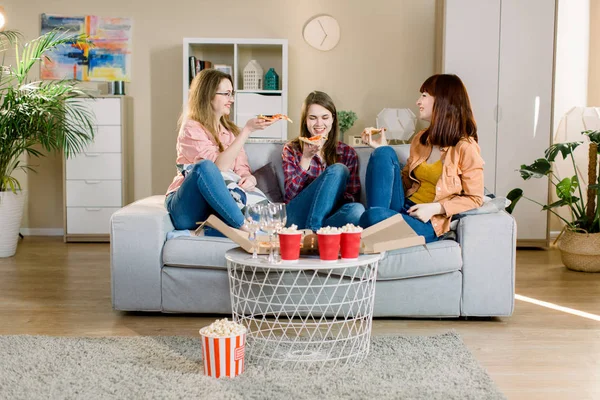 Kelompok tiga teman perempuan muda dengan pizza dan popcorn merayakan di interior rumah — Stok Foto