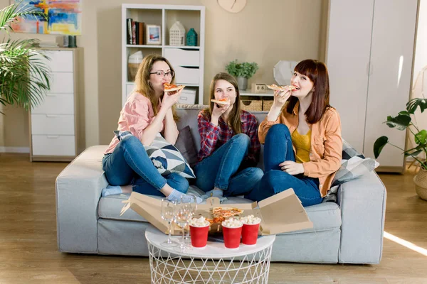 Kelompok tiga teman perempuan muda dengan pizza dan popcorn merayakan di interior rumah — Stok Foto