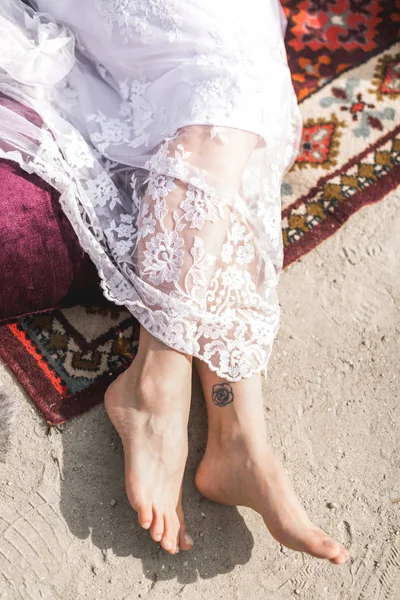 I piedi della sposa con tatuaggio si trovano sulla sabbia e sul tappeto — Foto Stock