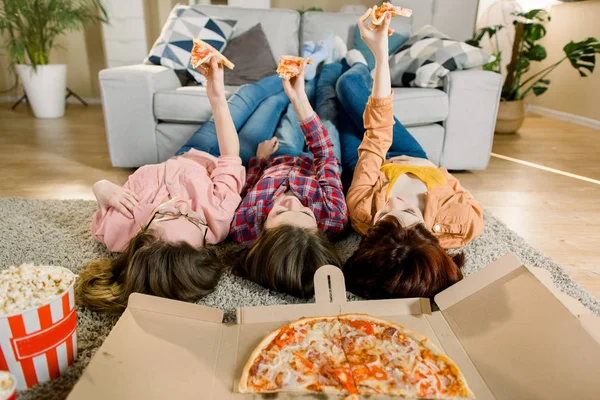 Pizza teslimatı, kadın partisi. Mutlu üç kız öğle yemeği, pizza, patlamış mısır ve şarap yeme, evde, ürün, closeup