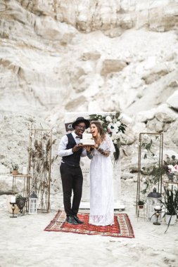 Boho mutlu güzel çift güzel rustik düğün pastası tutan giymek, kanyon açık havada düğün kemer ve süslemeleri arka planda ayakta