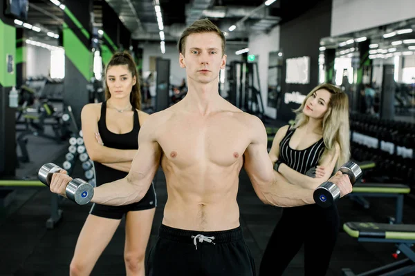 Retrato de estilo de vida de homem musculoso bonito com halteres no ginásio. Jovens treinando no ginásio com sinos — Fotografia de Stock