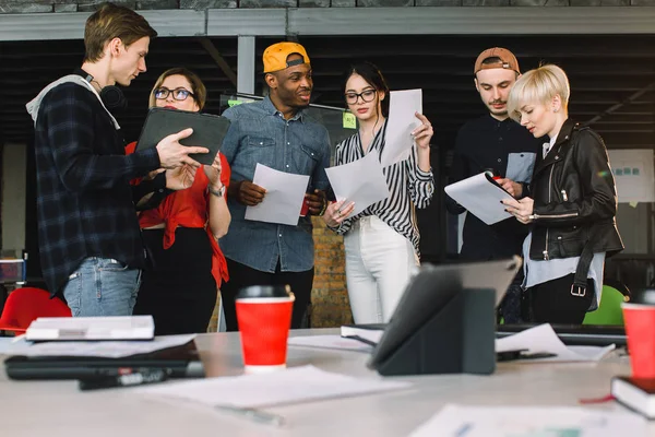 Möte Talking diskussion brainstorming kommunikationskoncept. Unga sex personer som arbetar tillsammans med papper och surfplattor i det moderna kontoret — Stockfoto