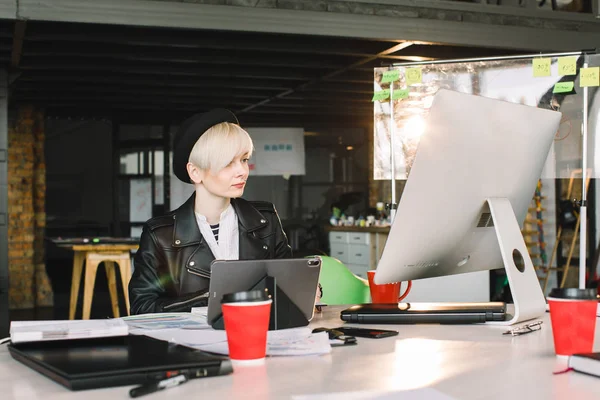 Koncentrerad ung vacker blond affärskvinna i casual Wear arbetar på PC och surfplatta i Bright Loft modern Office — Stockfoto