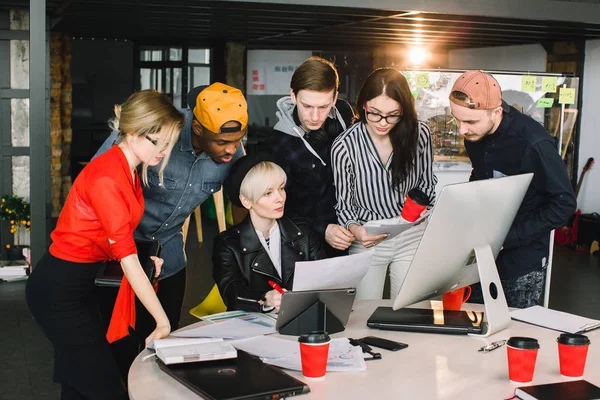 El trabajo en equipo y la creación de equipos es un éxito. Socios de arranque ocupados trabajando con computadoras y tabletas, en ropa casual, tan enfocados, discutiendo las ideas para una nueva estrategia de desarrollo en la oficina agradable —  Fotos de Stock