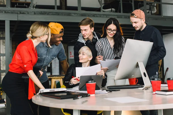 Mångskiftande grupp av affärsfolk som möts på modernt kontor. Kvinna i svart hatt visar hennes arbete inuti tablett till team med Happy Emotion. — Stockfoto