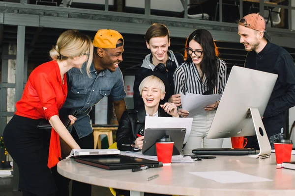Mångskiftande grupp av affärsfolk som möts på modernt kontor. Kvinna i svart hatt visar hennes arbete inuti tablett till team med Happy Emotion. — Stockfoto