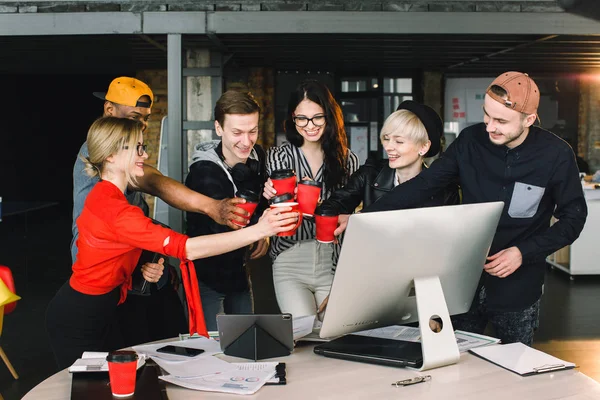 Grupp av internationella studenter eller arbetstagare i Loft kontor spottar koppar kaffe, sex kollegor i moderna arbete co-working utrymme pratar och leende när du står vid skrivbordet med bärbara datorer — Stockfoto