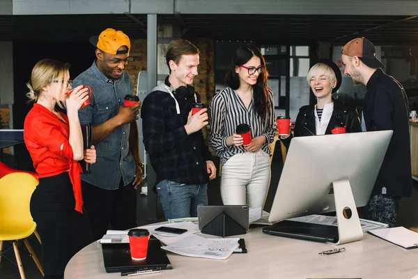 Pausa para relaxar no trabalho. Equipe de trabalho feliz durante o tempo de pausa no escritório moderno leve, conversando, tomando bebidas, sorrindo, todos vestidos com roupas casuais — Fotografia de Stock