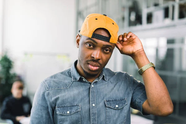 Vrolijke African American hipster Guy staande in Loft Office tijdens vrije tijd, gelukkig donkere gevild man genieten van zijn werk. jong team van freelancers werken in nieuw project op kantoor. — Stockfoto