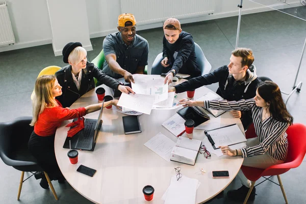 Top visning af multiraciale unge kreative mennesker i moderne kontor. Gruppen af unge erhvervsfolk arbejder sammen med laptop, tablet, smartphone, notesbog. Vellykket hipster team i coworking . - Stock-foto