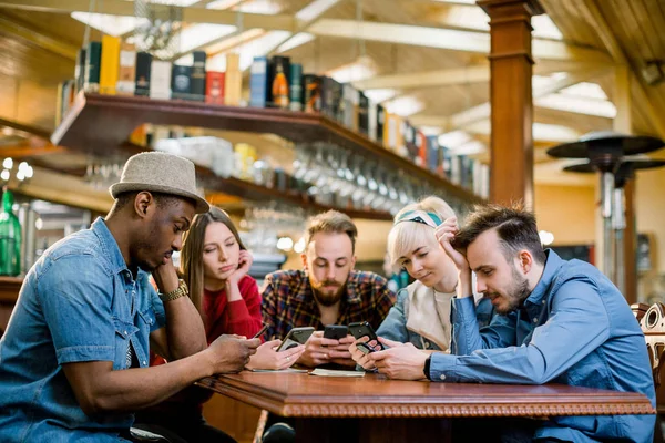 Genç üniversite öğrencileri ya da iş arkadaşları kafeteryada birlikte akıllı telefon kullanıyorlar, çeşitli gruplar. Günlük iş, kafede serbest iş, sosyal toplantı veya eğitim konsepti — Stok fotoğraf