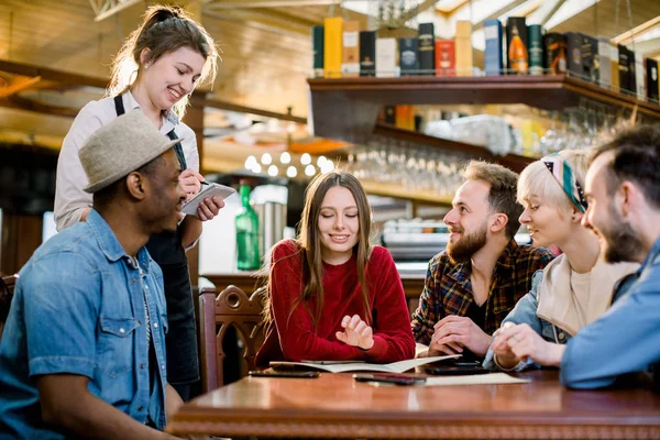 Siyah önlük içinde gülümseyen genç garson kafede müşterilerden sipariş alarak. eğlence, insanlar, yemek kafe ve tatil kavramı — Stok fotoğraf