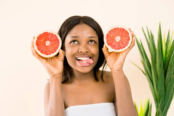 Afro-amerikai nő, a grapefruit fehér alapon, bemutatva a nyelvét. Szépség bőrápolás. Lemezterület másolása — Stock Fotó