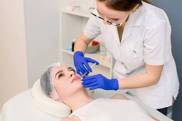Лікар-косметолог робить процедуру збільшення губ красивою жінкою в салоні краси. Косметологія Догляд за шкірою . — стокове фото