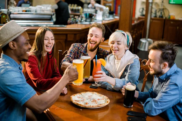 Mutlu beş arkadaş bir barda içki içiyor, Onlar bira ve pizza ile ahşap bir masada oturuyor. — Stok fotoğraf
