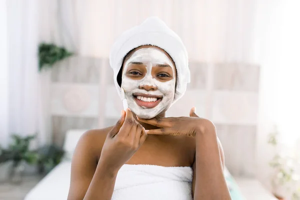 Maschera viso vitaminica. africano sorridente donna con un faccia in un maschera in spa — Foto Stock