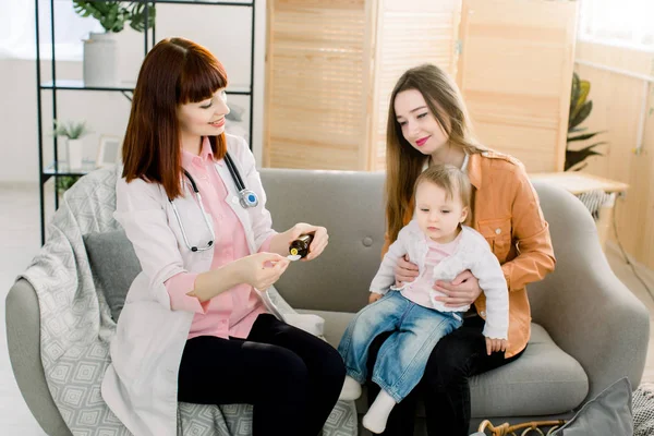 Jonge blanke vrouw arts geven siroop geneeskunde voor kleine baby meisje vanwege de griep, ziek kind en gezondheidszorg concept — Stockfoto