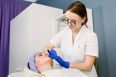 Güzellik merkezinde. Güzel görünümlü kadın doktor güzellik merkezinde yüz masajı yapıyor. Lüks güzellik salonunda spa yüz masajı olan sakin kız