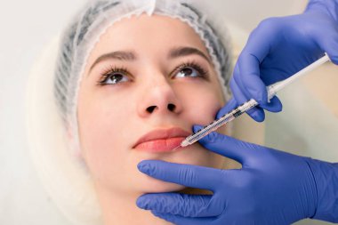 Güzel bir kadın dudaklarında bir dolgu enjeksiyonu alır. Dudaklarında botoks enjeksiyonu alan genç kadın, yakından