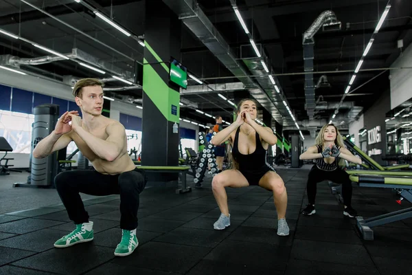 Fitness, esporte, treinamento, ginástica e conceito de estilo de vida - grupo de pessoas sorrindo se exercitando no ginásio, fazendo agachamentos — Fotografia de Stock