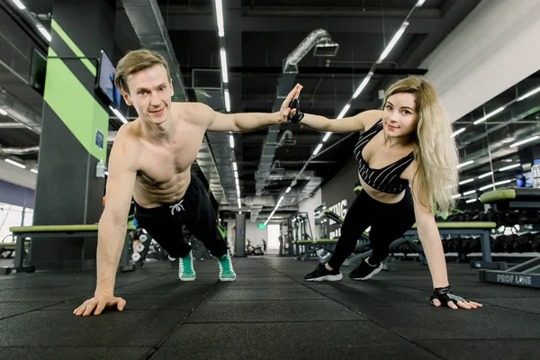 Para robi pompki na treningu w siłowni. Sportowy para robi push-upy i dając wysoki pięć. Wnętrze siłowni. — Zdjęcie stockowe