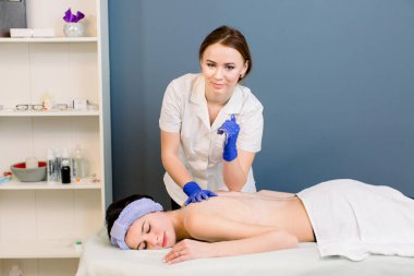 Kadın genç güzellik ile spa salonunda masaj geri almak. Genç gülümseyen tıbbi kozmetolojist iş yerinde kameraya bakıyor.