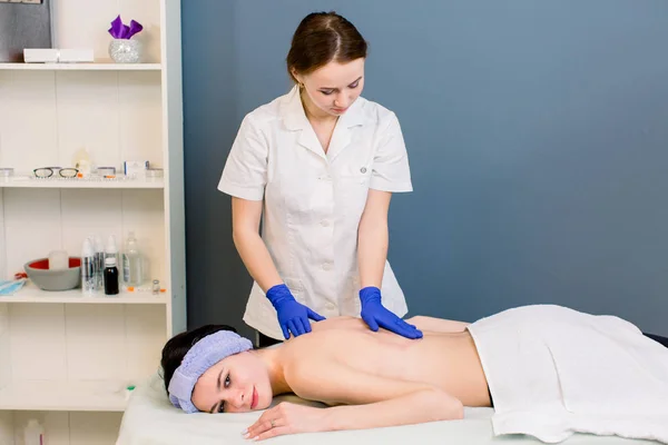 Pronti per il massaggio - l'olio si riversa sulle donne nel centro benessere della spa. Massaggio corpo professionale per bella ragazza in cosmetologia gabinetto o salone di bellezza . — Foto Stock