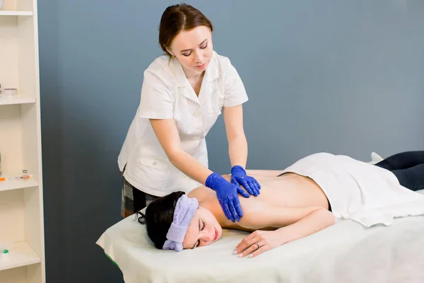 Giovane donna cosmetologo facendo massaggio alla schiena al salone termale per la giovane bella ragazza — Foto Stock