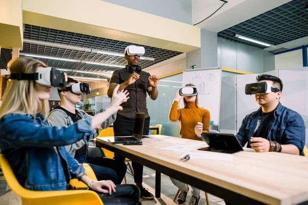 A jövő most. Magabiztos kreatív fiatalok beállító virtuális valóság headset és mosolygó ülve munkahelyi helyen irodai — Stock Fotó