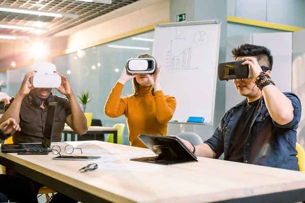 Multirasistiska bästa vänner ha kul bär Virtual Reality glasögon i Creative Office. Unga människor som använder ny teknik — Stockfoto