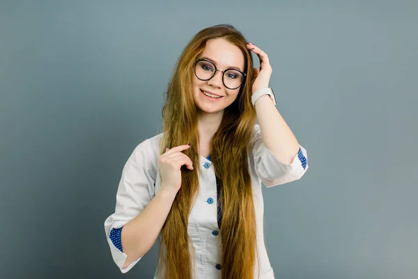 Retrato de uma jovem médica atraente de casaco branco, isolado em fundo cinza — Fotografia de Stock