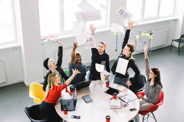 Vue du dessus de beaux beaux beaux cadres joyeux attrayants portant casual assis au loft industriel lieu de travail intérieur à l'intérieur avec les bras levés — Photo