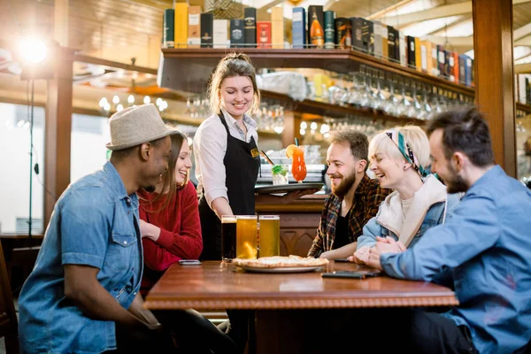 Kapalı restoran ve içecekler ve bira ile gülümseyen garson gülümseyen genç çeşitli arkadaşlar Portresi. — Stok fotoğraf