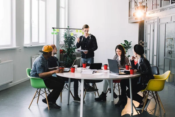 Jovens multirraciais pessoas criativas no escritório moderno. Grupo de jovens empresários estão trabalhando em conjunto com laptop, tablet, telefone inteligente, notebook. Equipa hipster de sucesso em coworking. Freelancers. — Fotografia de Stock