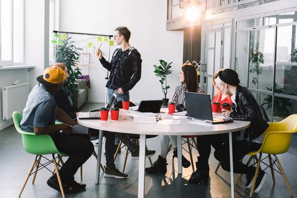 Gruppe lässig gekleideter Geschäftsleute, die im Büro Ideen diskutieren. Kreative Experten versammelten sich am Besprechungstisch, um die wichtigen Fragen des neuen erfolgreichen Startup-Projekts zu diskutieren — Stockfoto