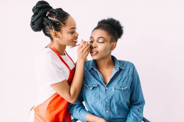Genç güzel Afro-Amerikan kadın Afrikalı makyaj sanatçısı tarafından profesyonel makyaj uygulayarak. Stüdyo çekimi