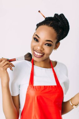 Güzel genç Afro-Amerikan güzellik kadını beyaz izole, fırçalar ve göz farları makyaj seti tutan